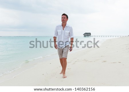 Man walk on the background of beautiful beach with white sand and cloudy sky