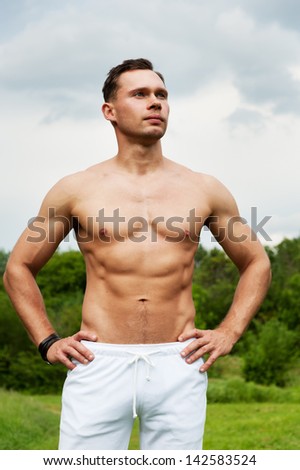 Man in white pants stands on the grass in the park