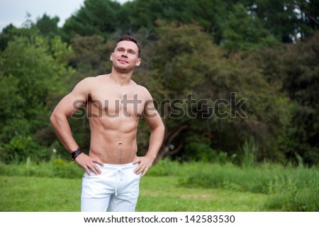 Man in white pants stands on the grass in the park