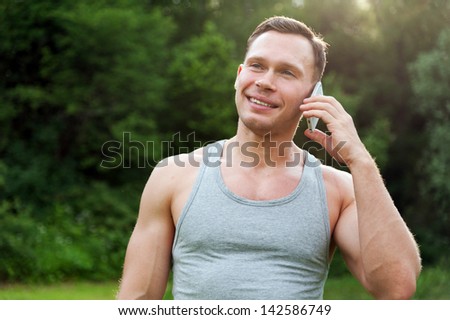Man stands and talking on a telephone in the park