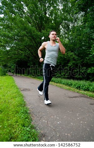 Man in black pants runs on the road in the park