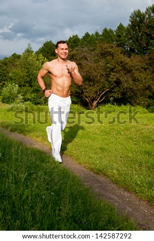 Man in white pants runs on the road in the park