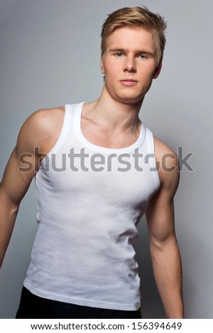 Portrait of young handsome blond man wearing t-shirt against grey background