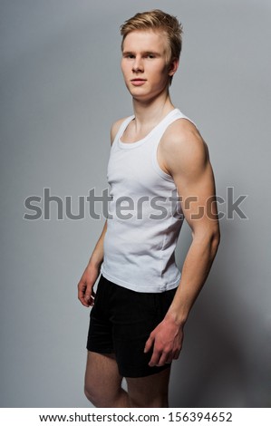 Portrait of young handsome blond man wearing t-shirt against grey background