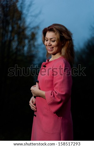 Beautiful woman in pink coat walks in the Park, autumn background