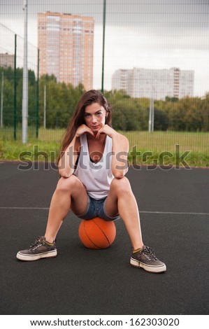 Woman Sitting On Basketball On Sports Playground
