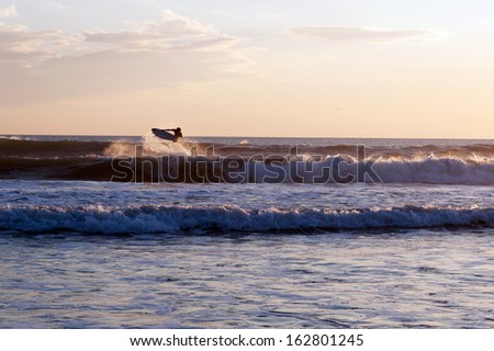 Single surfer at sunset in the ocean with waves