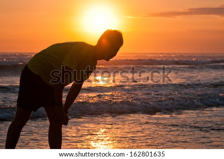 Silhouette of young man on the beach with ocean view at the sunset