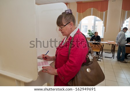 MOSCOW, RUSSIA - SEPTEMBER 8, 2013: Woman fills election ballot with the candidates for mayor of Moscow on September 8, 2013 at the local election commission in Moscow.