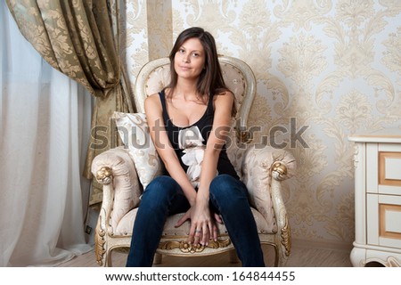 Young pregnant woman sits on chair at home interior