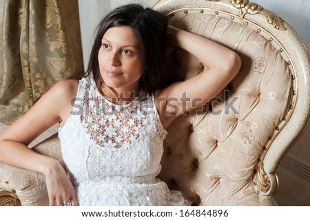 Young pregnant woman sits on chair at home interior