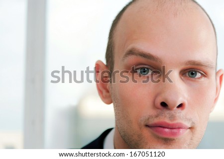 Closeup portrait of a serious handsome businessman with raised eyebrow in office background