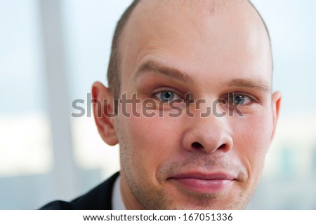 Closeup portrait of a serious handsome businessman with raised eyebrow on office background