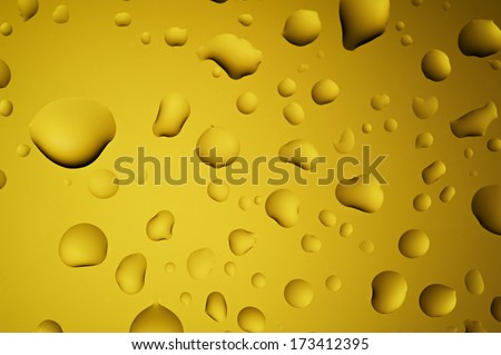 Close-up macro water drops on glass with gold or yellow background