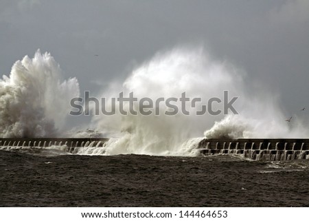 Big ocean waves over pier in a windy day