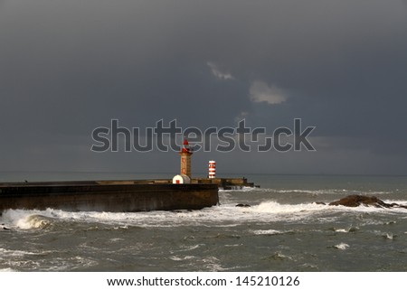 Sun and rain over the north portuguese coast seeing pier, lighthouse and beacon of the entry of Douro river, Porto