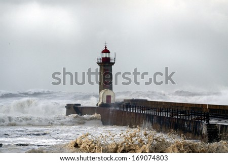 Lighthouse and stone pier in a stormy day