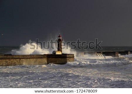 Storm waves over lighthouse of the harbor of river Douro, Portugal. Late evening light.