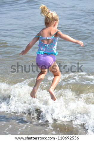 little girl jumping in the ocean