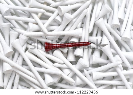 red golf tee on pile of white tees