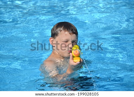 boy in swimming pool playing with water gun