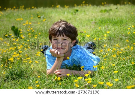young boy leaning chin in hand laying down in grass outside