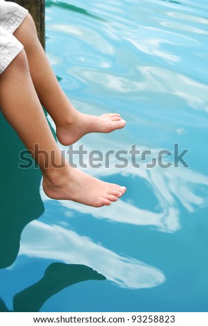 boy hanging feet over water