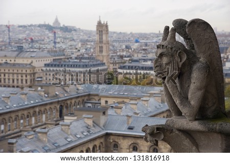 Stone gargoyle (Chimera) overlooking the city of Paris from the tower of the Notre Dame with the SacrÃ?Â?Ã?Â©-Coeur in the background