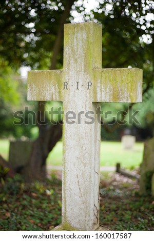 RIP written on a headstone in the form of a cross on a graveyard