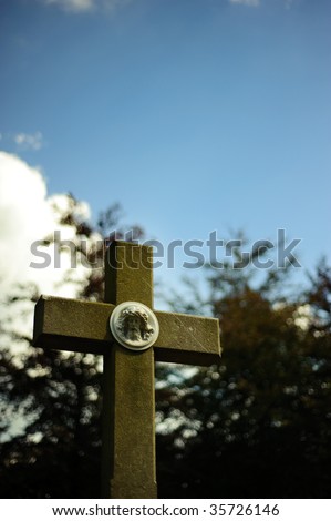 Dark photo of cross with sculpture of Jesus on a cemetery