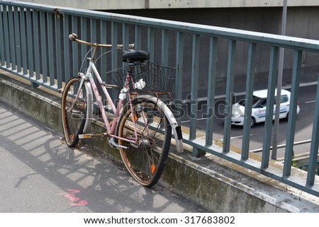 broken forgotten bicycle on a bridge railing in Berlin