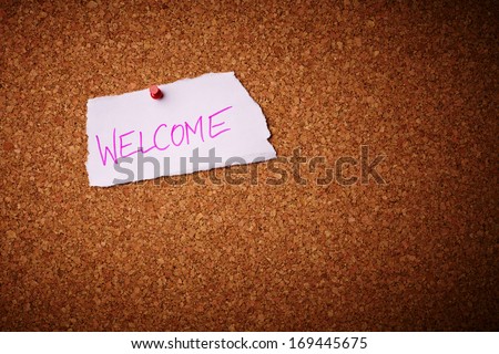 Welcome - Cut out letters pinned on a cork notice board.