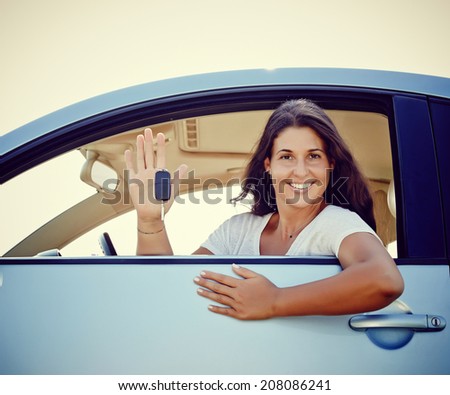 Happy smiling woman is showing keys to her new car, rental car.