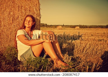 Mother Nature - Young woman sitting at a hay Bale in nature enjoying her life.