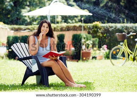 Attractive young woman reading a book in the garden