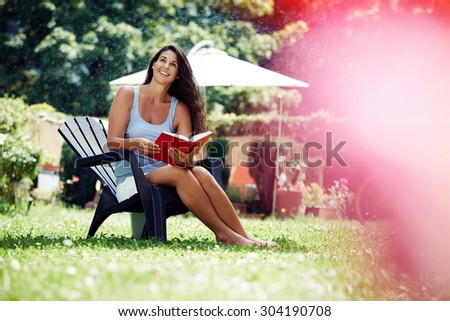 Attractive young woman reading a book in the garden