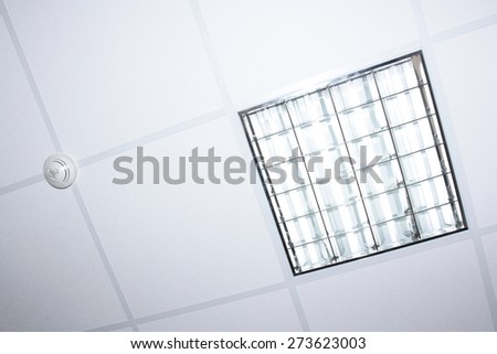 fluorescent lamp illumination and fire detector on modern office interior ceiling