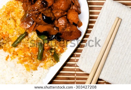 chicken meat and risotto with vegetables and sushi chopsticks on beige cloth, asia food composition