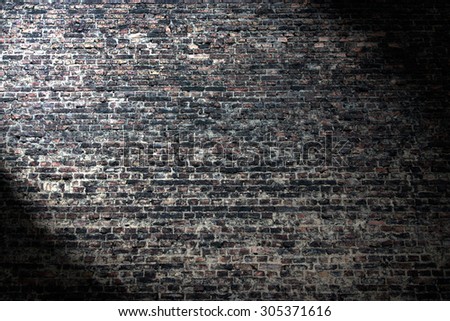 grunge background, dark brick wall texture and beam of spot light highlight in the corner