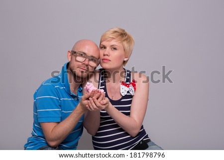 Young attractive couple pregnant mother and happy father holds a pink socks for his daughter over gray background