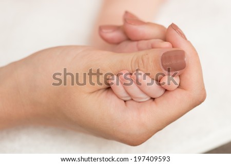 Baby\'s hand gripping adult finger. Close up