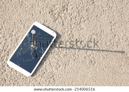 metal nail and smart phone with a broken screen over the stone surface