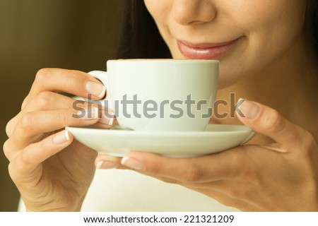 Coffee. Beautiful Girl Drinking Tea or Coffee in Cafe. Beauty Model Woman with the Cup of Hot Beverage. Warm Colors Toned