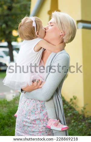 mother kissing her daughter in the park