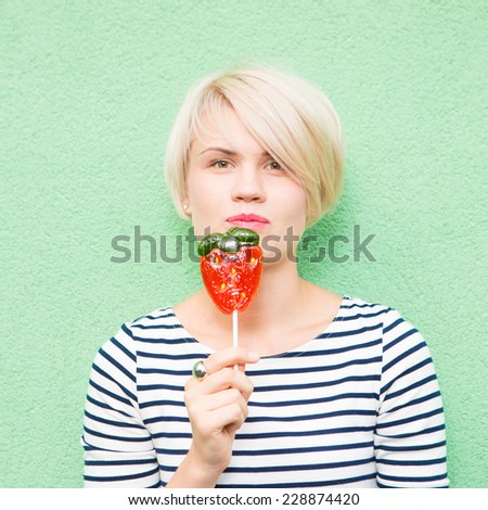 Young sexy woman sucking lollipop. Urban style. Outdoors, lifestyle.