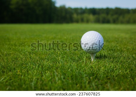 Golf ball on a tee against the golf course with copy space. close-up