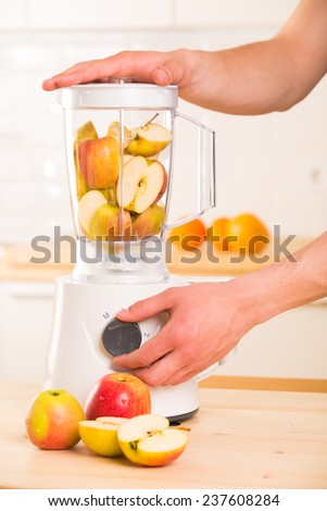 White blender with apples on a wooden table. Kitchen