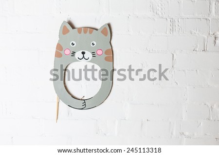 Bright cardboard mask on a white brick wall. Consept card. Cat