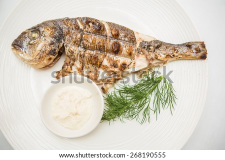 Grilled organic dorada fish white dish. Top view