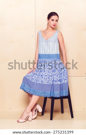 Full body slim woman in blue sundress on wooden background